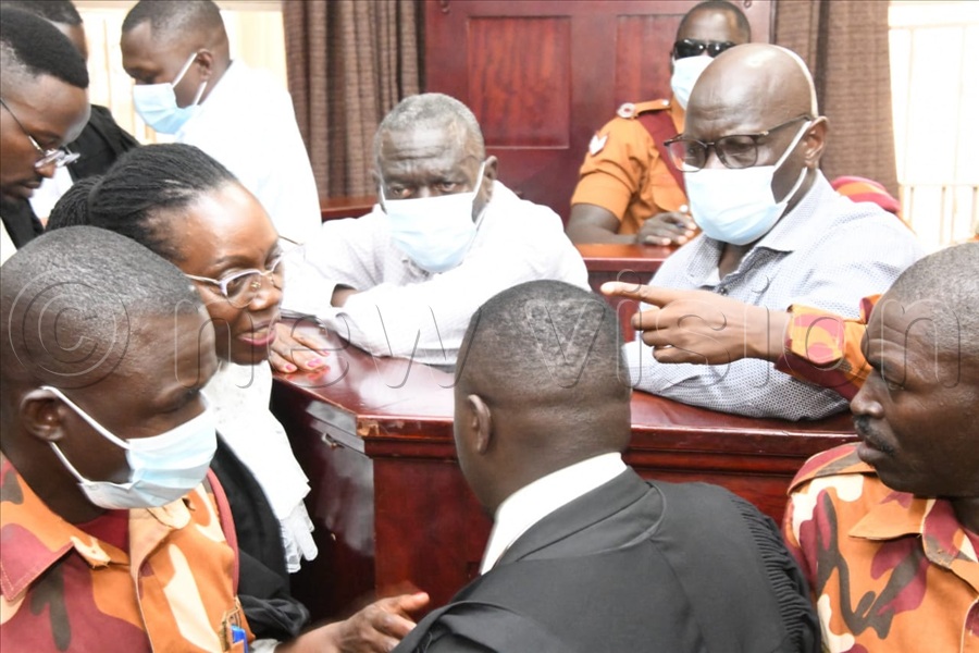 Besigye in the dock interacts with his lawyers. (All Photos by Mpalanyi Ssentongo)