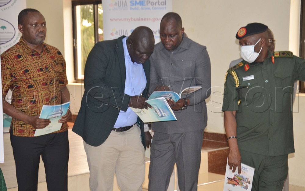 Amuru RDC, Osborn Geoffrey Oceng (second in coat) and James Nabinson Kidega, RDC Agago, checking the Acholi investment profile book as Deputy Chief Coordinator of Operation Wealth Creation (OWC), Brigadier General Godfrey Muwanguzi, looks on. (Photo by Jackson Kitara)