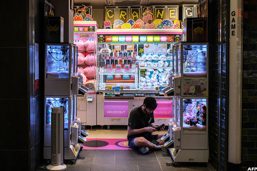 A man pays to play a claw crane game machine inside a shop at the Akihabara district of Tokyo. (AFP)