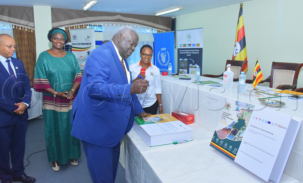 Sam Engola appending signature on the newly launched multi hazard integrated early warning system alongside the national anticipatory action roadmap at Imperial Resort hotel in Entebbe municipality on Friday. (Credit: Julius Luwemba)