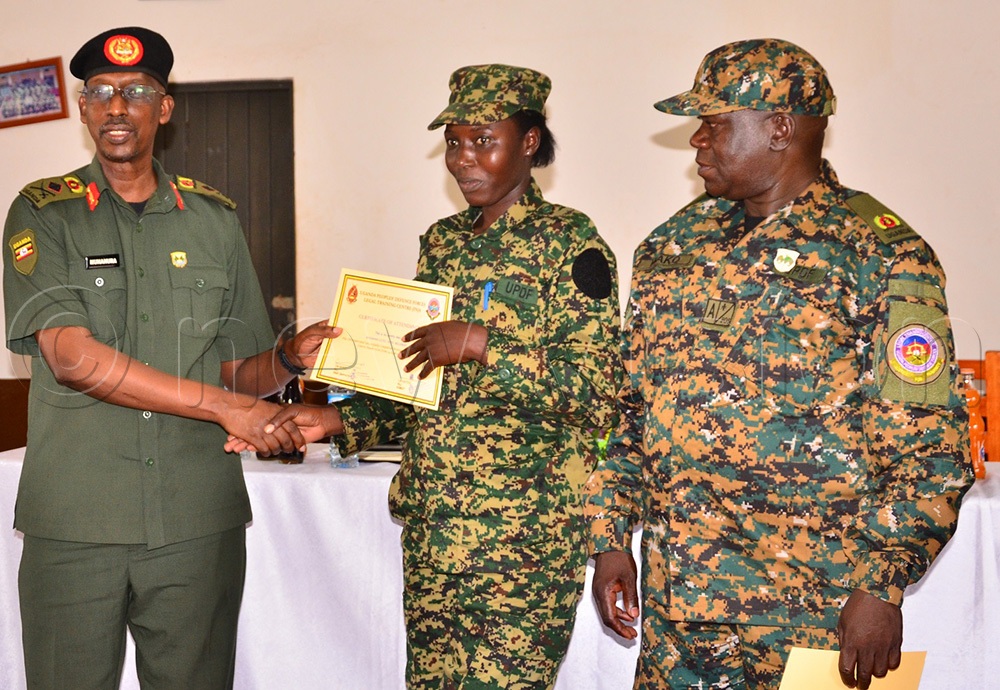 Wako (R) looking on as L-CPL Mildred Apio, who was among the 3 female officers, was awarded a certificate by Munanura at the LTC in Gaddafi Barracks, Jinja city on Friday. (Photo by Jackie Nambogga)