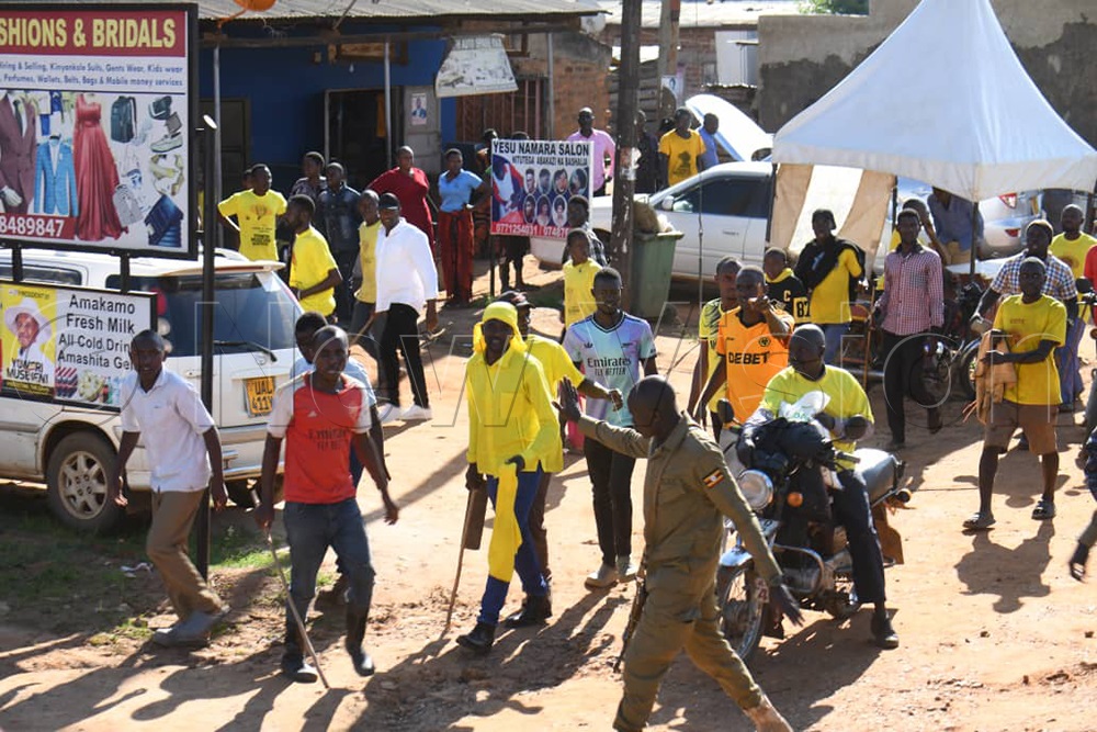 A police officer restraining NRM supporters. (Credit: Ponsiano Nsimbi)