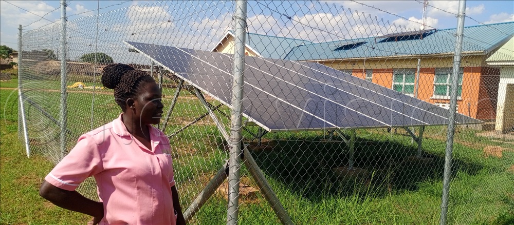 Health worker standing next to the solar panel installed at the facility compound.