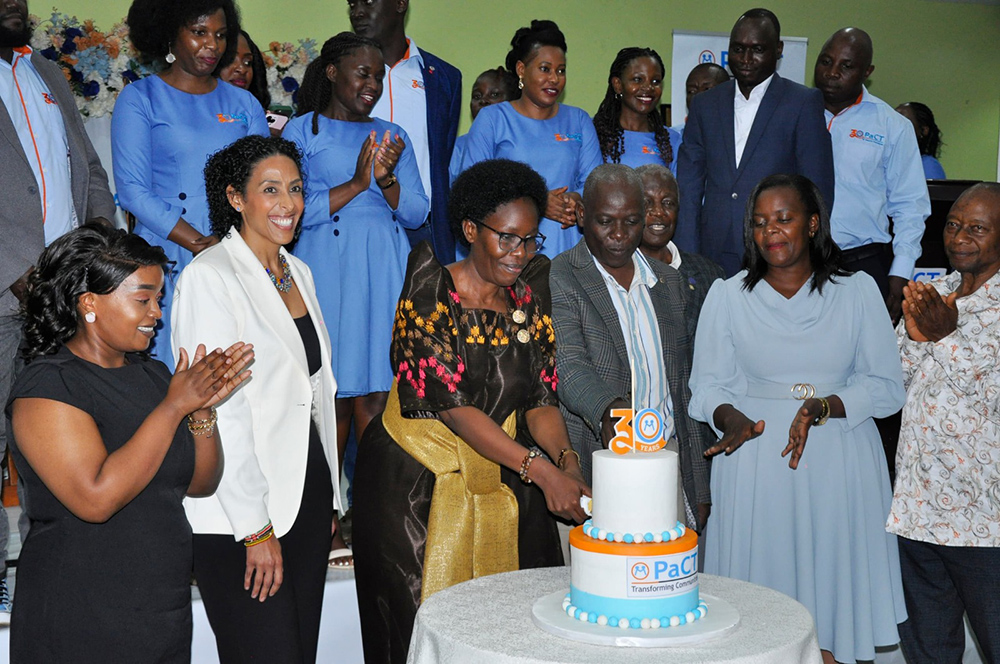 Lands minister Judith Nabakooba cutting cake while other look on and others clap during the commemoration of 30 years of Partners for Community Transformation (PaCT). (Courtesy photo)