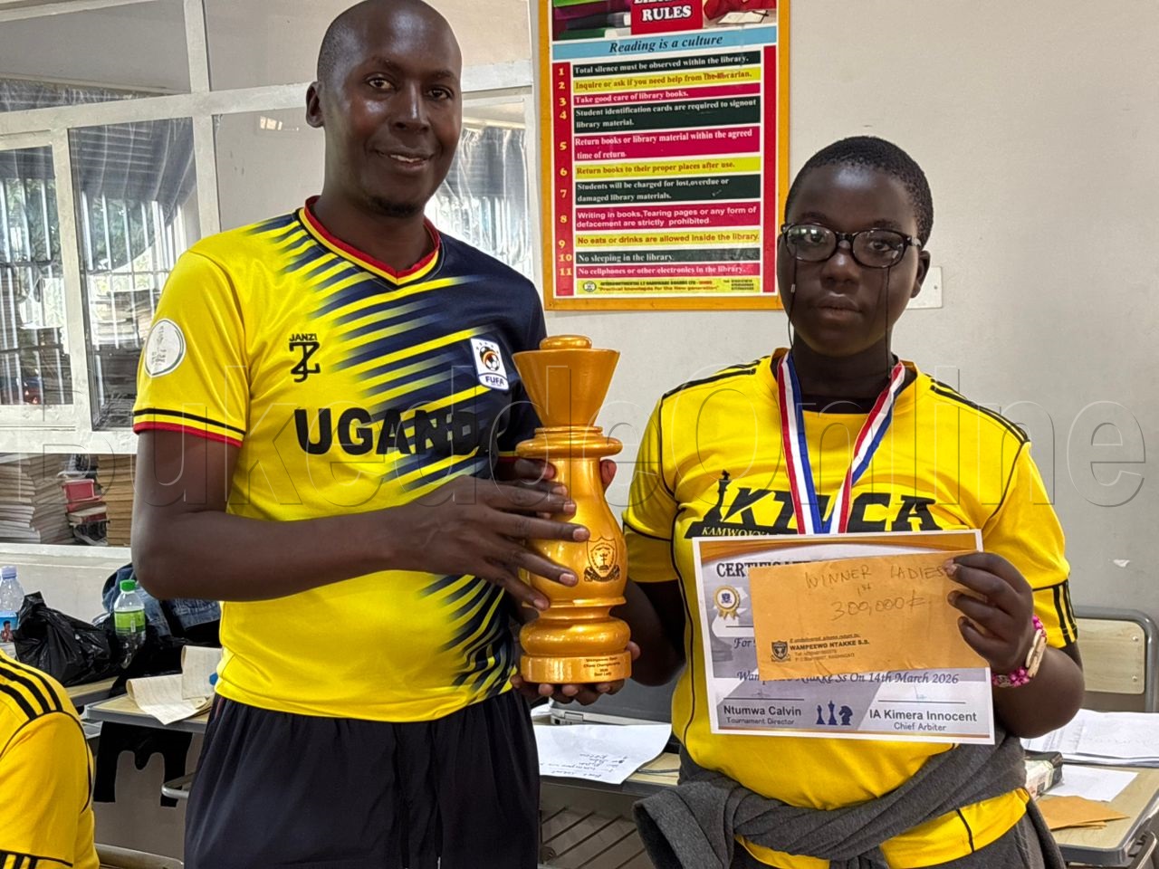 Akulira omuzannyo gwa chess mu Buganda Moses Nkonge nga akwasa Juliet Asaba ekirabo oluvannyuma lwokuwangula mu mutendera gwabawala