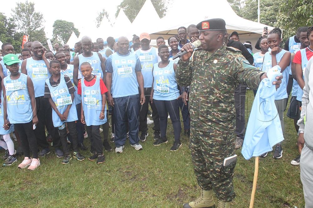 An army officer attached to the Mountain division based in Fort-Portal city flagging of runners of the 5km run of the Save River Mpanga marathon. (Credit: Samuel Amanyire)