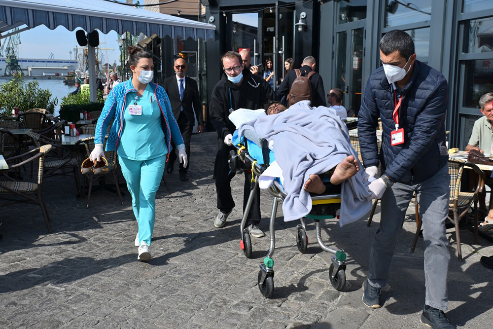 An injured crew member from a ship struck by drones in Bulgaria's exclusive economic zone is moved on a stretcher after he was rescued, at the Varna harbour on October 6, 2026. Bulgarian authorities launched a major search on October 6 for the missing crew of a ship that sank in the Black Sea after drones hit two vessels in what the prime minister slammed as an "absolutely unacceptable" attack. (Photo by AFP)