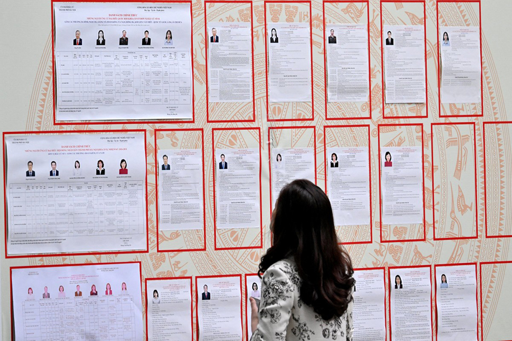 A woman looks at the lists of candidates inside a voting station in Hanoi on March 15, 2026. Polls opened in Vietnam with voters casting ballots for members of the National Assembly, the country's top legislative body that serves mainly to ratify decisions by the ruling Communist Party.