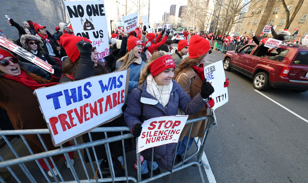 Nurses shout and hold signs as they strike outside Mount Sinai Hospital in New York on January 12, 2026. According to US media reports, nearly 15,000 nurses went on strike Monday morning  after no agreement was reached ahead of the deadline for contract negotiations. (Photo by TIMOTHY A. CLARY / AFP)