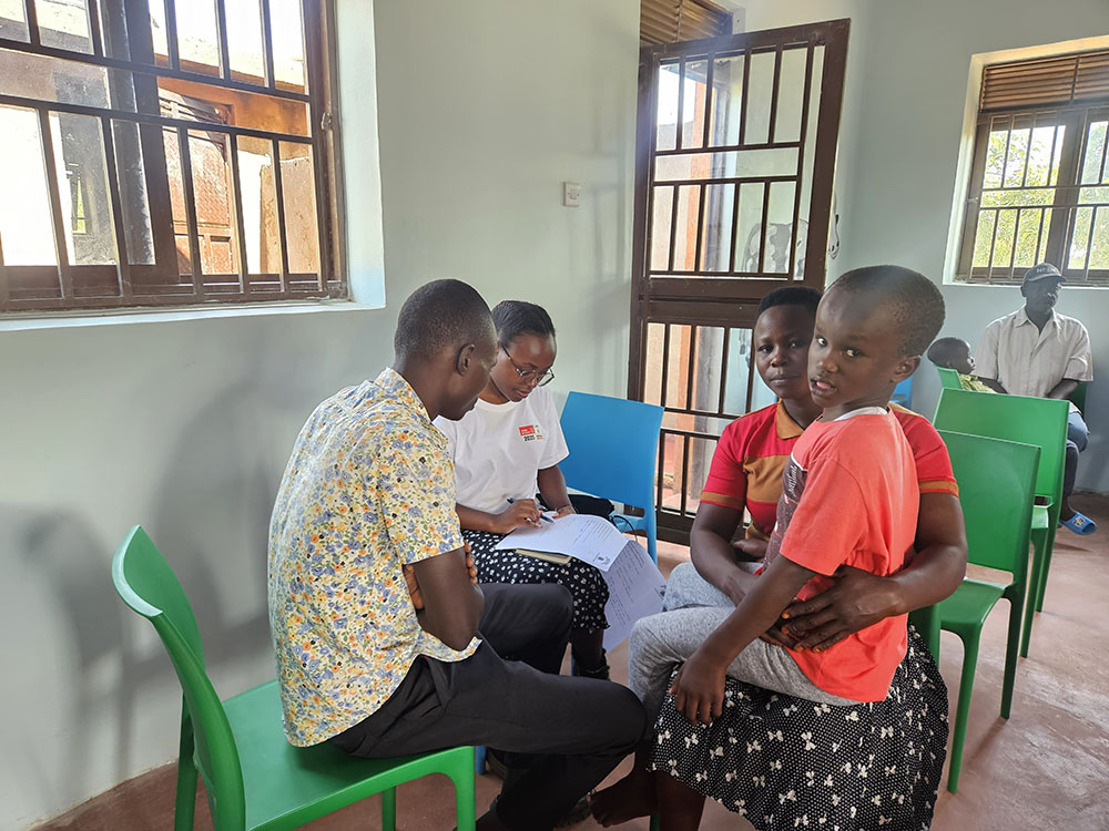 A student from University of West England attending to a child with hydrocephalus who is under the care of Hidden People project. (Photo by Lydia Nabwire)