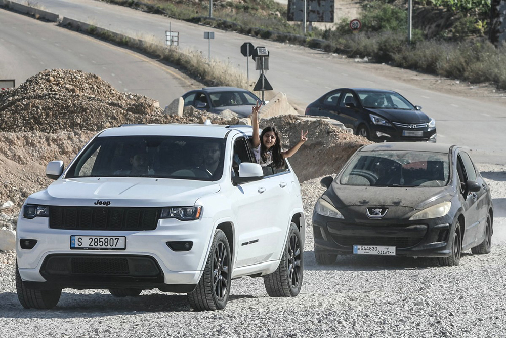 A girl flashes the V-sign from a vehicle as displaced residents cross the Bourj Rahal bridge on their way to their village in southern Lebanon on June 15, 2026. (AFP)