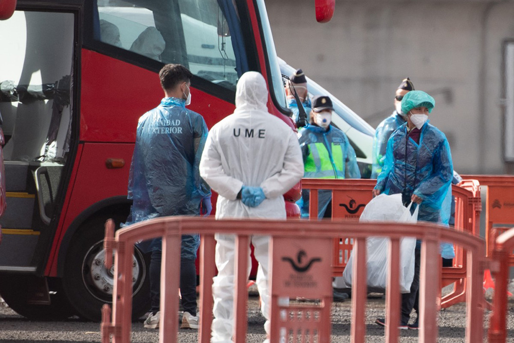 A passenger (R) wears a protective suit and mask while boarding a military bus as passengers and crew are evacuated from the Dutch flagged hantavirus-stricken cruise ship MV Hondius at the industrial port of Granadilla de Abona on the island of Tenerife in Spain's Canary Islands on May 10, 2026. (Photo by JORGE GUERRERO / AFP)