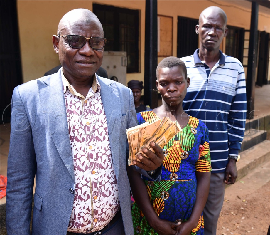 RDC Soroti Hajji Imuran Mulunga displaying the recovered five million that the LC2 stole from Betty Akajo (middle)
