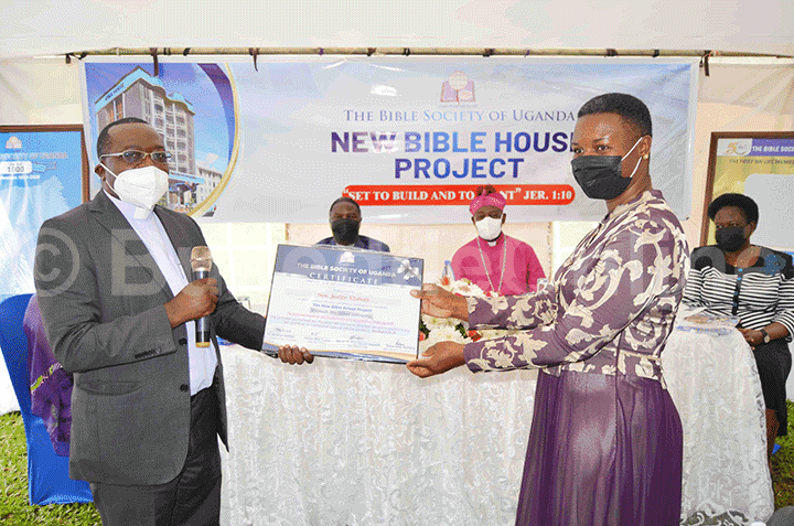 Fr. Dr. Mark Richard Ssajjabi (ku kkono) ng'akwasa Hon. Justine Khainza ssatifikeeti ye.