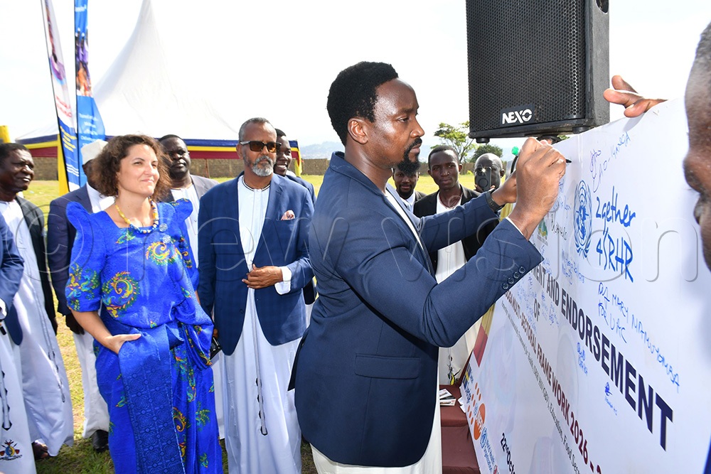 Kyabazinga of Busoga William Gabula Nadiope IV (right) signing on a commitment and endorsement board after the launch of the Busoga Regional Multi-Sectoral Partnerships and Accountability Framework 2026-2030 as Laura Lafuente Criado (left), the Programme Coordinator in charge of Gender and Youth at UNFPA and Busoga Kingdom's Second Deputy Prime Minister Alhaji Osman Ahmed Noor (middle) look on. (Photo by Donald Kiirya)