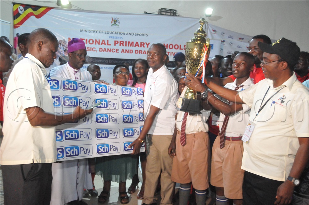Rt. Rev.Fred Sheldonb Mwesigwa, the Bishop of Ankole Diocese bishop handing over a trophy to Buganda Road Primary School who took the second position in the National MDD festival 2025.