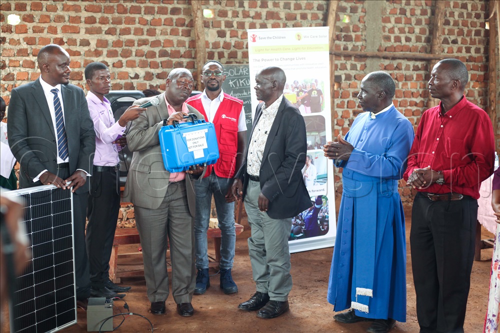 Wakiso District Education Officer, Kiyingi Fredrick Kinobe (with a solar case) handing it over to the school management.
