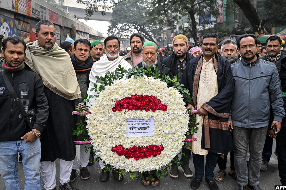 Supporters of Bangladesh's former prime minister Khaleda Zia carry a wreath to mourn her death as they gather before the funeral ceremony in Dhaka on December 31, 2025.