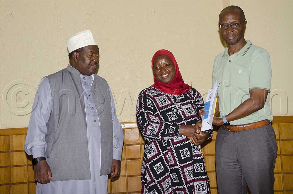 Moses Byaruhanga, Senior Presidential Advisor In-charge of Political Mobilization (Right) handing over travel documents to Aisha Tumwebaze, one of the beneficiaries from Kibale district (Centre), as Abbas Sekyanzi Muluubya, General Secretary Uganda Muslim Supreme Council (Left), looks on. This was during the flagging-off ceremony of President Museveni sponsored Muslim pilgrims to Mecca held at Gaddafi Mosque on Friday, 22 August 2025. (Credit: Colleb Mugume)