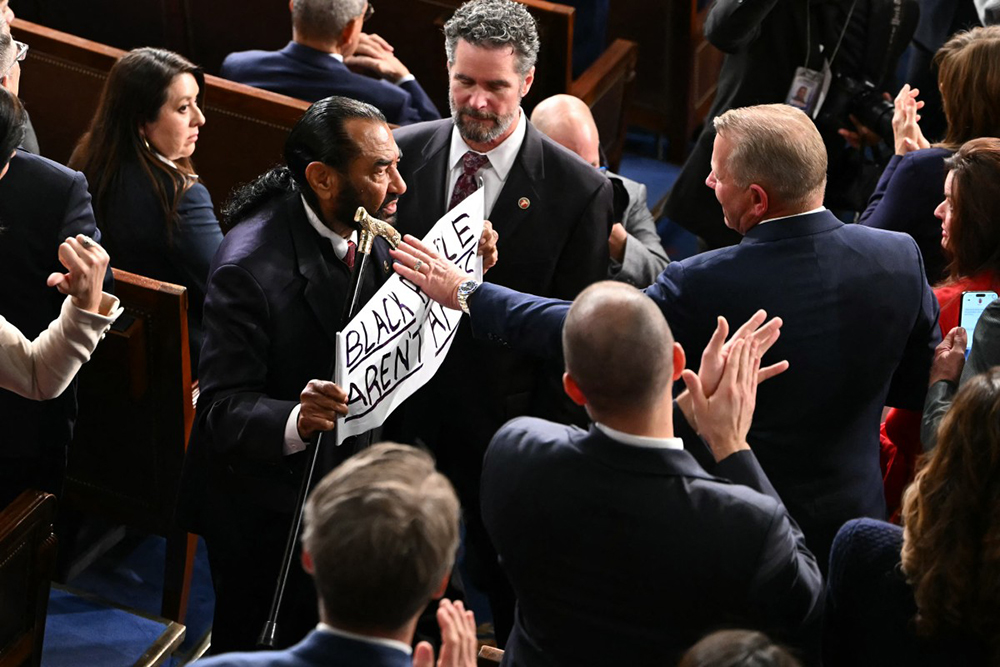 US Representative Al Green, Democratic from Texas, exits as he holds a sign reading "Black people aren't apes" as US President Donald Trump delivers the State of the Union address in the House Chamber of the US Capitol in Washington, DC, on February 24, 2026. 