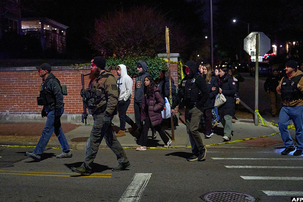 Law enforcement officers escort students near the Barus & Holley engineering building at Brown University campus in Providence, Rhode Island, on December 13, 2025