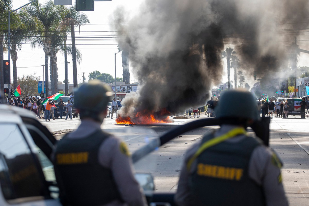 A car burns as law enforcement clashes with demonstrators during a protest following federal immigration operations, in the Compton neighborhood of Los Angeles, California on June 7, 2025. (Photo by RINGO CHIU / AFP)