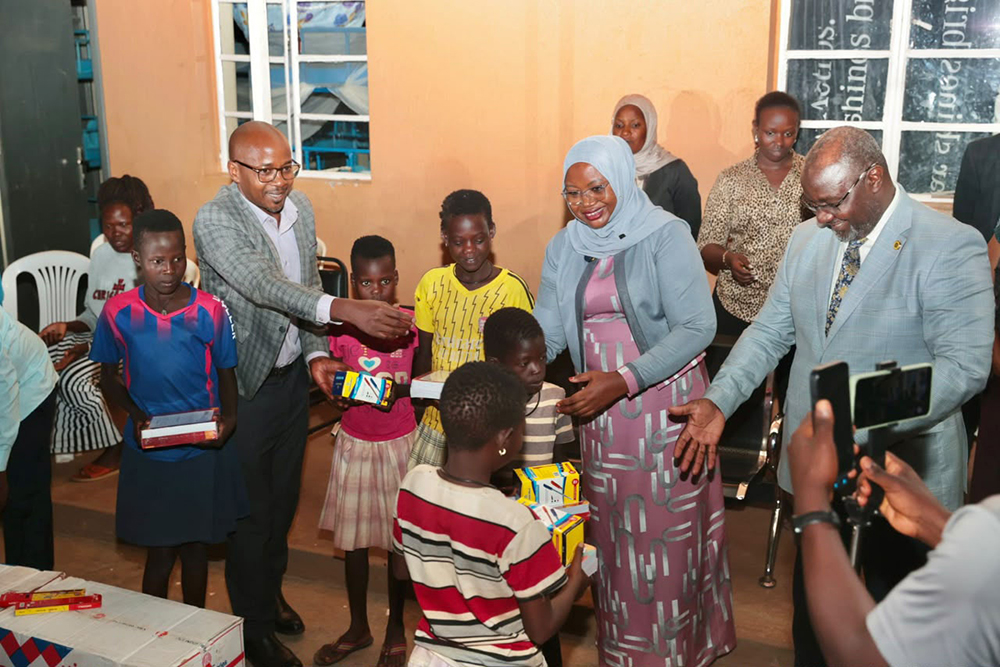 The Kampala Capital City Authority (KCCA) executive director, Hajati Sharifah Buzeki and the deputy ED Benon Moses Kigenyi hand over scholastic materials to repatriated street children before they were sent to Napak District.