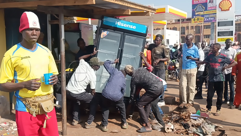 Some people helping a trader to remove her fridge from Lamogi Ber Bus Terminal. This is one of the kiosks marked last month for eviction. (Photo by Rosemary Anena)
