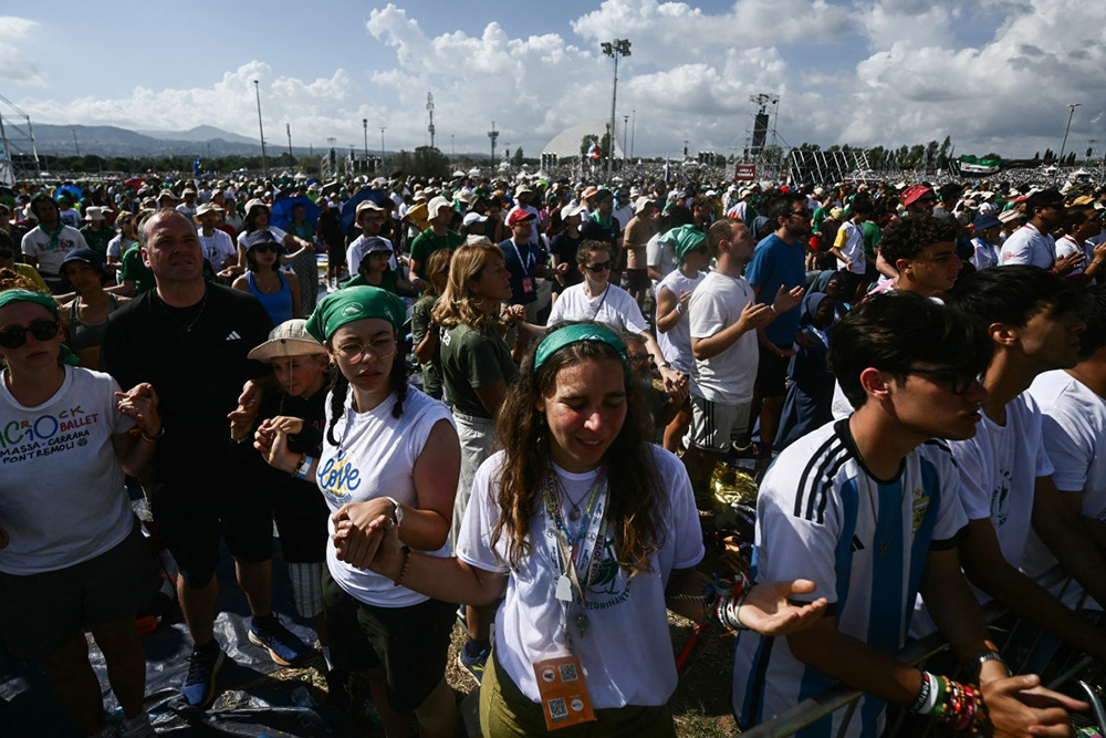 Young faithfuls hold hands during an open-air mass in the Tor Vergata district of Rome, as part of Jubilee of Youth, on August 3, 2025. Pope Leo XIV presided over a final mass in Rome for over one million young people. (Photo by Filippo MONTEFORTE / AFP)