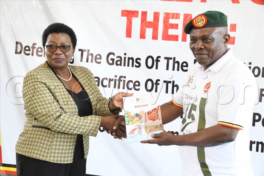 Vision Group Senior Producer News & Current Affairs Hellen Mukiibi hands over text books to Brig.Gen. Michael Kibuye, also the director Civil Military Cooperation.