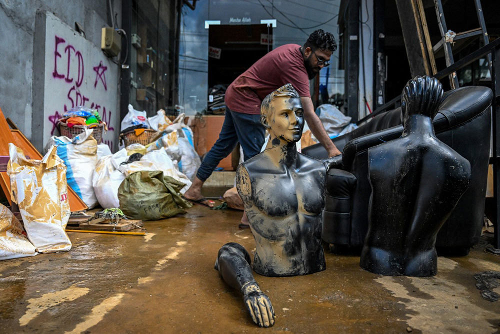 A man clears sludge from a cloth shop following flash floods in the aftermath of Cyclone Ditwah in Gampola town, in Kandy district on December 4, 2025. (Photo by Ishara S. KODIKARA / AFP)