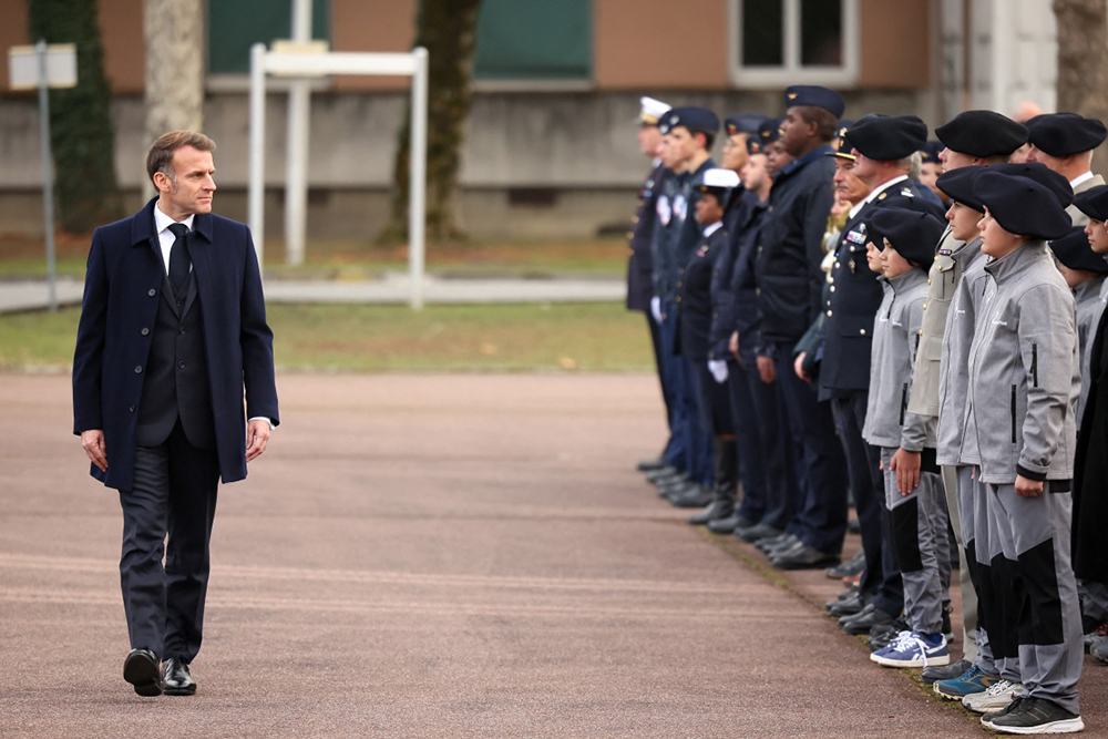 France’s President Emmanuel Macron (L) reviews the troops and students of an army high school ahead of delivering his speech to unveil a new national military service at the military base in Varces, French Alps, on November 27, 2025. 