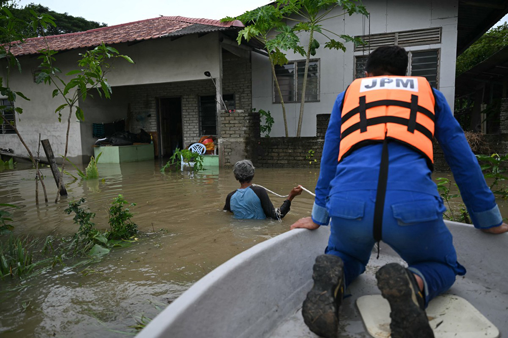 A rescue worker looks out from a boat as his team arrives at a home submerged by flood waters in Kangar in northern Malaysia's Perlis state on November 27, 2025, as severe flooding affected thousands of people in the region following days of heavy rain. 