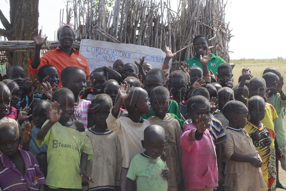 Korobe, the head teacher with Esther Arinaitwe, manager NiE at Vision Group with pupils at Lokodiokodio 4 Community School in Napak district.