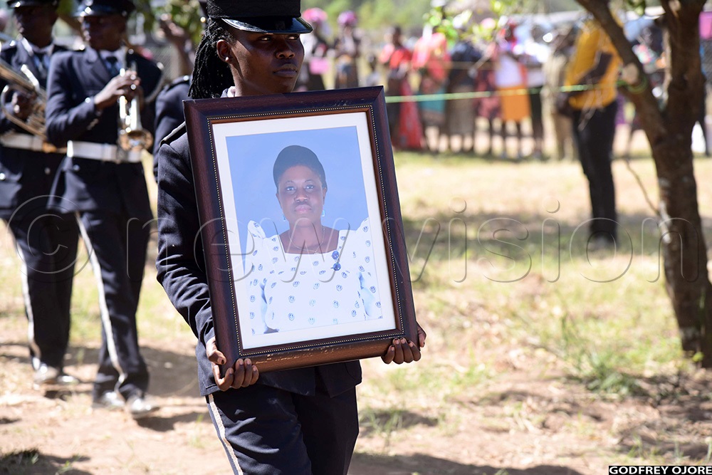 A Police officer carrying the potrait of the late MP Stella Apolot Isodo. (Photo by Godfrey Ojore)
