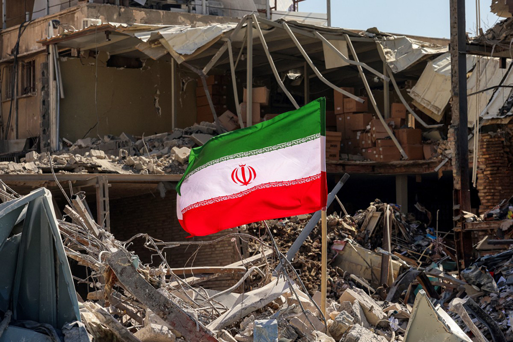 An Iranian flag is placed amids rubble and debris next to a destroyed residential building near Ferdowsi square in Tehran on March 3, 2026. (AFP)