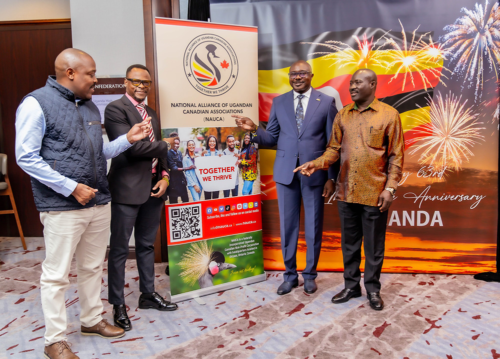 The head of the State House Diaspora Unit (R), Allan Kajik, the Acting High Commissioner of Uganda to Canada (2R), Deputy head of the Diaspora Unit, Henry Wabyona (L) and the chairperson of NAUCA, Justus Mirembe, point their fingers at the NAUCA banner after the launch. (Credit: Uganda High Commission Canada)