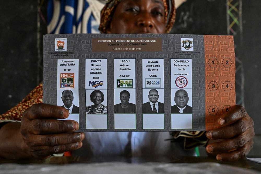 An Independent Electoral Commission of Ivory Coast (CEI) official holds up a ballot paper showing the four presidential aspirants. (Photo by Issouf SANOGO / AFP)