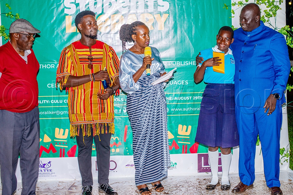 Amuru resident district commissioner, Geoffrey Osborn Oceng (in Blue suit), hugging Sharon Oroma of Ocer Campion Jesuit College after she finished as runner-up in the written poetry, after Sandra Auma (in centre), an adjudicator, as Prof. Charles Nelson Okumu (extreme left) during awarding the winners. (Photo by Jackson Kitara)