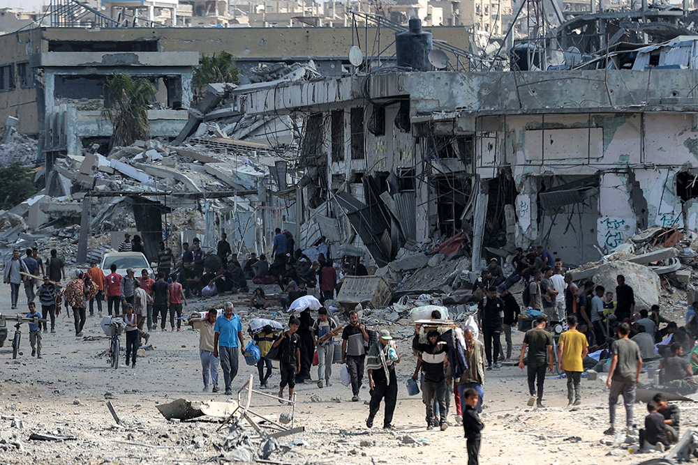 People walk along a destroyed road past heavily-damaged buildings in the centre of Khan Yunis in the southern Gaza Strip on October 10, 2025, as the displaced return to their homes after Israeli forces' withdrawal. (Photo by Omar AL-QATTAA / AFP)