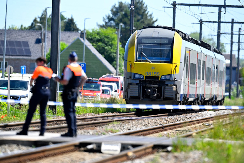Police officers inspect the site of an accident after a train (R) crashed into a school bus, at the railway crossing Vierhuizen in Buggenhout, some 20kms north of Brussels on May 26, 2026. (Photo by JOHN THYS / AFP)