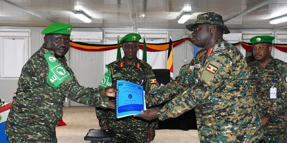 Col Francis Aragamoi hands over the report and other serviceable materials to the incoming duty contingent commander, Col Jude Rukubya, during the handover ceremony. (Courtesy)