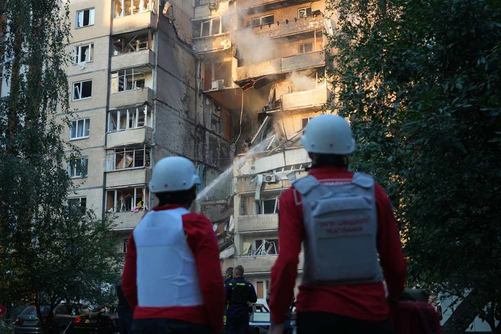 Firefighters work to extinguish a fire as paramedics stand in front of a heavily damaged residential building following Russian drone and missile strike in Kyiv on September 7, 2025, amid the Russian invasion of Ukraine. (Photo by OLEKSII FILIPPOV / AFP)