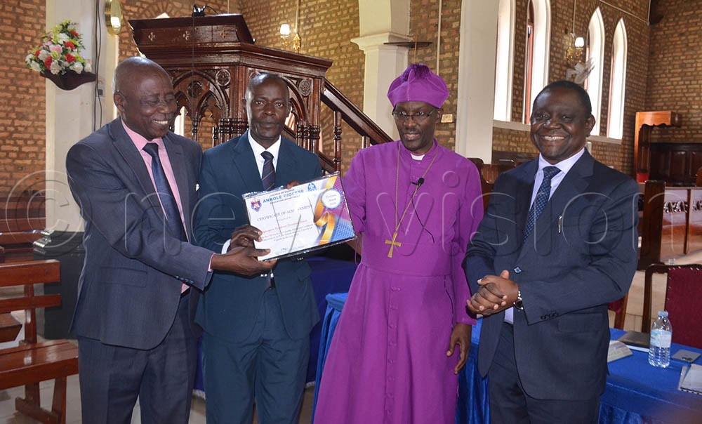 (L-R) Nathan Mugume chairman board Kigaragara Vocational SS, Julius Begumya head teacher Kigaragara Vocational SS, receiving a certificate of achievement from Bishop Fred Sheldon Mwesigwa and Moses Kasakya, the Executive Director of Technical Vocational Education and Training (TVET) during the Thanksgiving Service held at St. James Cathedral-Ruharo on Tuesday. (Credit: Abdulkarim Ssengendo)