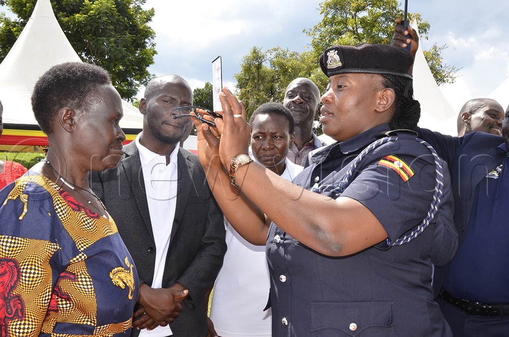 Masindi DPC Pensive Ukasima helping a resident put on her newly acquired reading spectacles. (Photo by Yosam Gucwaki)