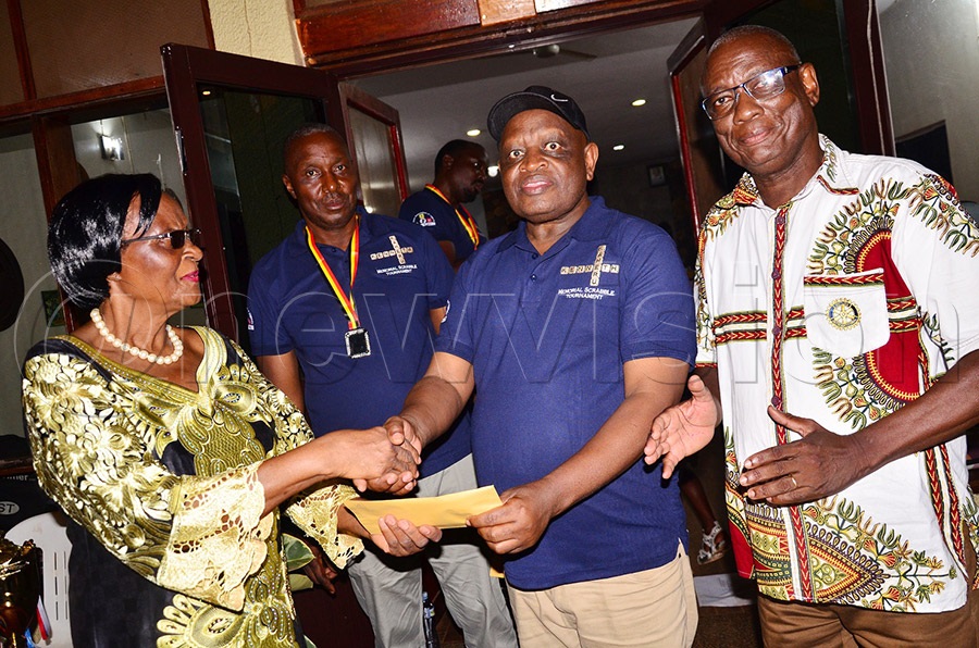 Stella Kaheru (L) handing a cash prize of sh1m to Kenya's Stanley Njoroge who came third in the Kenneth Kaheru memorial scrabble tournament, right is SAU president Nelson Kyagera