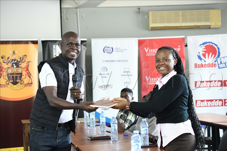 Oprah Nkalubo law student at Makerere university receives a gift from Jonah Waiswa, the in charge of stakeholder engagement at Bank of Uganda. (Credit: Maria Wamala)