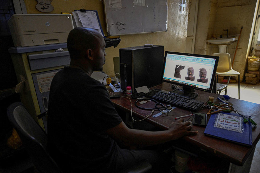 A Sudanese volunteer responsible for handling burial procedures for unidentified bodies in the capital, Khartoum, reviewing images of a victim at Omdurman's Al-Nao Educational Hospital, the capital's main functioning health facility, amid the conflict between the Sudanese army and the paramilitary RSF, who have been locked in a war, since April 2023, that has killed tens of thousands and displaced nearly 12 million people.
