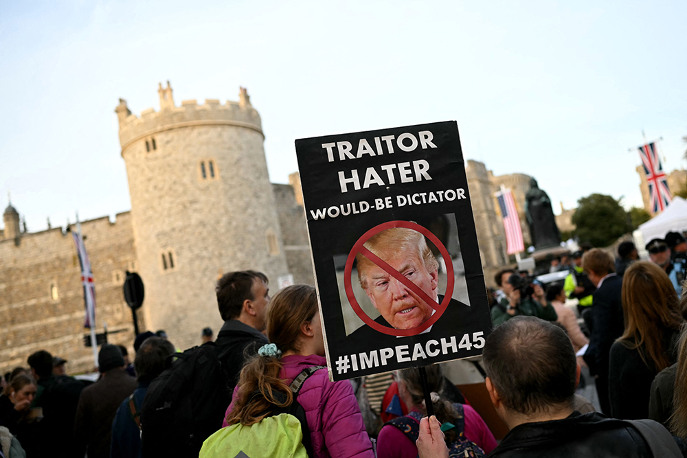 A demonstrator holds a placard during a protest against the forthcoming State Visit of US President Donald Trump, outside Windsor Castle in Windsor on September 16, 2025. US President Donald Trump is set arrive in the UK late September 16, 2025 for a second State Visit with his wife Melania, made at the invitation of King Charles III. 