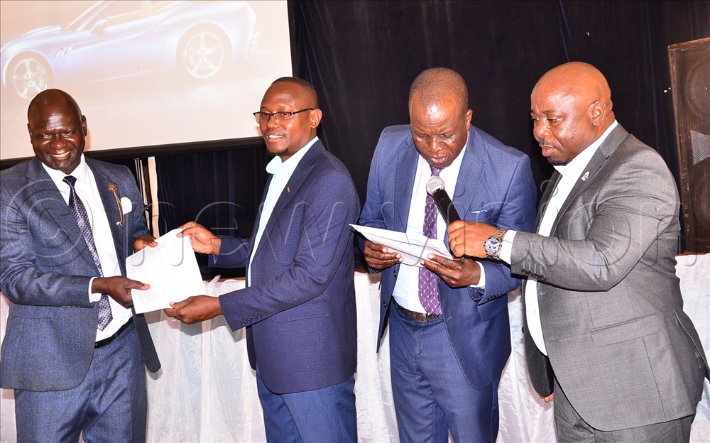 Livingstone Mbago (L) the Victoria Nile headteacher recieving a certificate from Kasolo as Baliraine (R) aided Otimong to announce the best schools in mock in Jinja city.